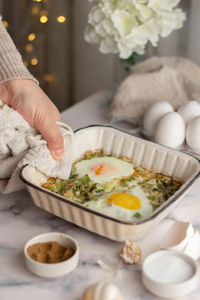 Hand of a Person Placing a Dish in a Baking Pan onto a Table