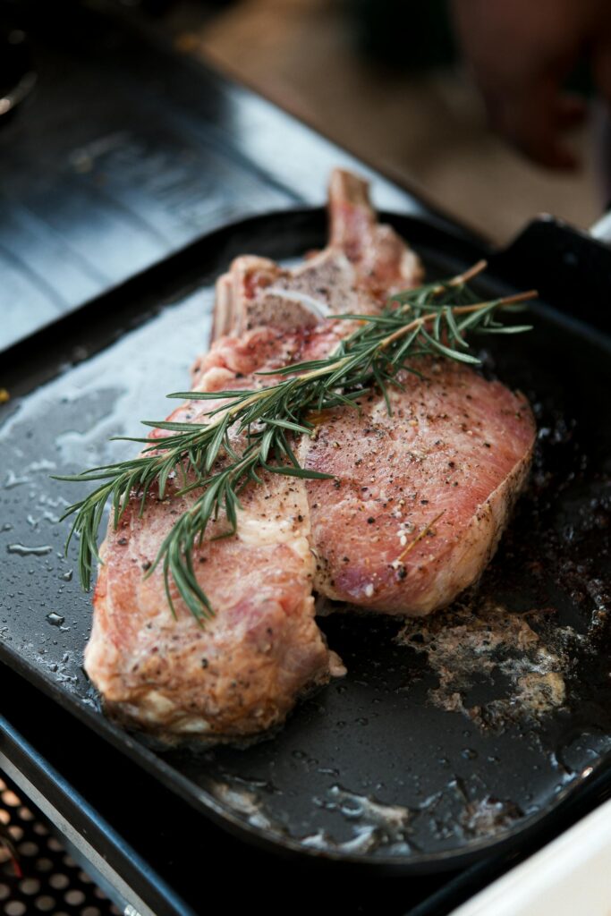 Pork Chops on a Frying Pay with a Sprig of Rosemary